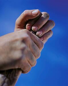 Hands holding stick against blue sky