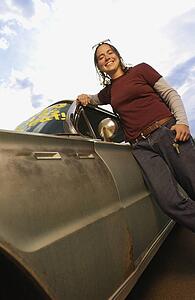 Low angle view of a girl posing by the car