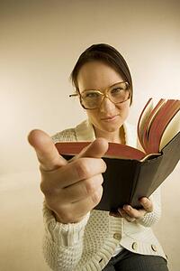 A woman holding book and pointing to the camera