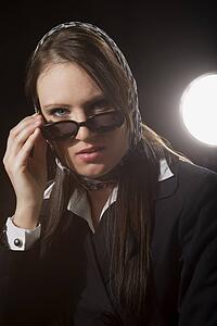 A young woman peering over sunglasses