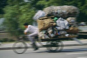 Man hauling a load of bags on a cycle rickshaw in Beijing, China