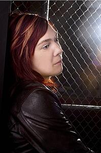 Young woman standing along chain link fence