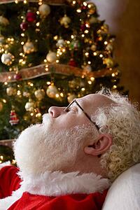 Santa Claus asleep by the Christmas tree