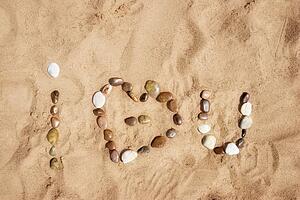I love you written as 'i heart u' in stones on the sand