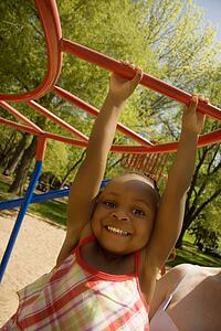Young girl swinging on playground equipment