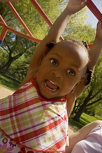 Young girl hanging from playground equipment