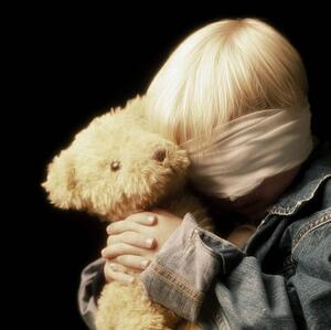 Boy with bandage on eyes and holding teddy bear