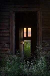 Door to abandoned home with warm inviting window light 