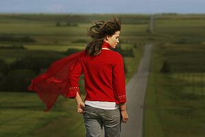Woman walking on road surrounded by fields