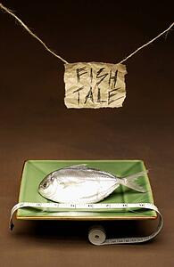 Fish on a plate with a measuring tape and sign saying "fish tale"
