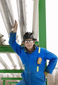 Industrial worker standing under piping