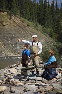 Father and sons on river shoreline 