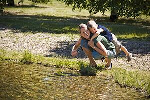 Mother giving son piggyback near lake