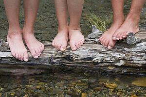 Children standing on a log in a stream 
