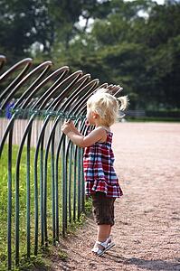 Girl standing against a fence in a park