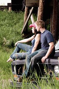Couple sitting on the hood of a vehicle