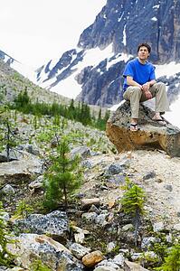 Front view of a man sitting on rock