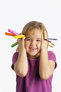 A girl holding crayons and markers