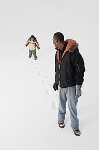 Boy following dad in the snow