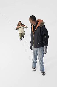 Boy following dad's footprints in the snow