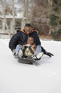 Father and son sledding on snow