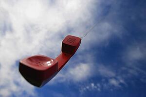 A telephone receiver dangling from the sky