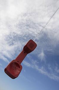 A telephone receiver dangling from the sky