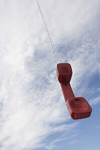 A telephone receiver dangling from the sky