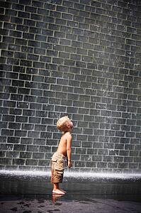 A boy standing beside a wall fountain, Chicago, Illinois, USA