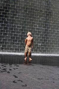 A boy standing beside a wall fountain, Chicago, Illinois, USA