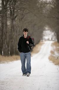A teenage boy walking on a snow-covered path