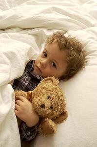 Boy laying in bed with teddy bear