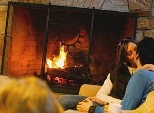 Couple kiss in front of fireplace