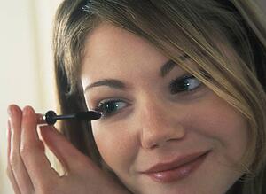 Young woman putting on mascara