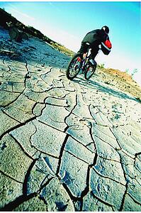 Cyclist riding on dried and cracked mud