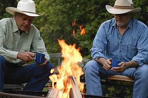 Two men sit by the fire