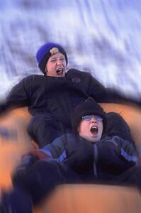 Boys sliding down a hill on a raft