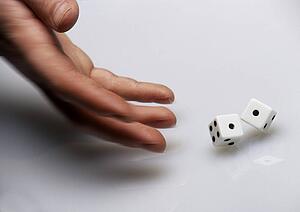 Hand rolling dice on white surface