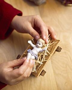 Child playing with figure of baby Jesus