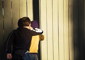 Two boys peeking through the fence