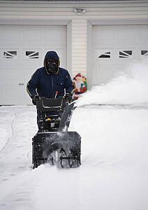 Man operating a snow blower