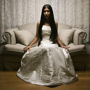 Portrait of an Indian bride sitting on a love seat.