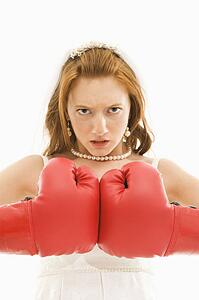 Caucasian bride with boxing gloves togther.
