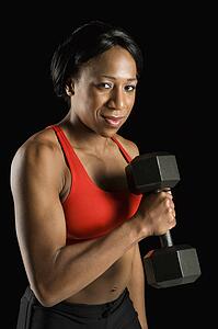 African American young adult woman holding dumbbell and looking at viewer.