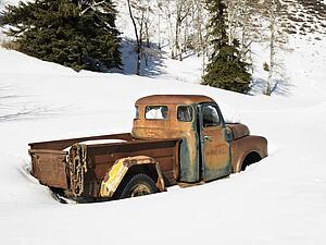 Old rusted classic truck in snow covered field