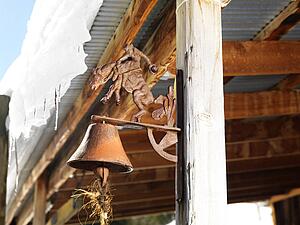 Rusted bell on side post of shed