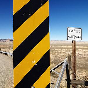 Yellow and black caution sign with Utah landscape in background.