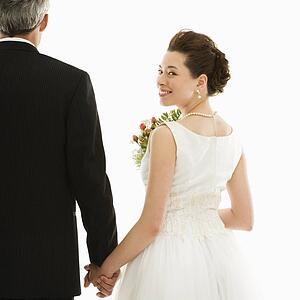 Bride looking over her shoulder while holding groom's hand