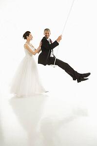 Bride pushing groom in swing set