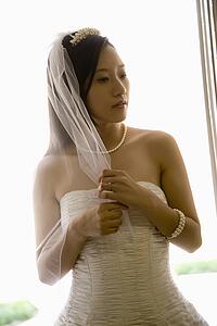 Portrait of an Asian bride holding her veil.